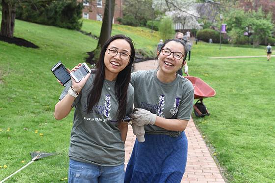 Photo of two international students on Chatham University's Shadyside Campus, pausing while volunteering to plant flowers